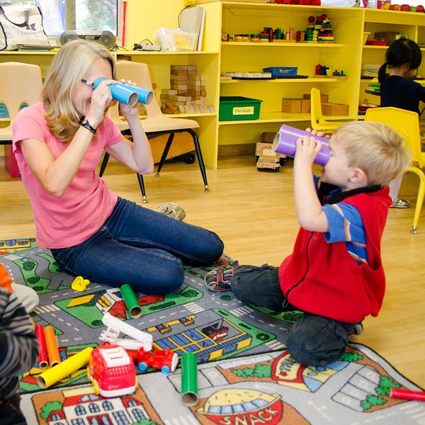 teacher and student looking at each other through cardboard binoculars